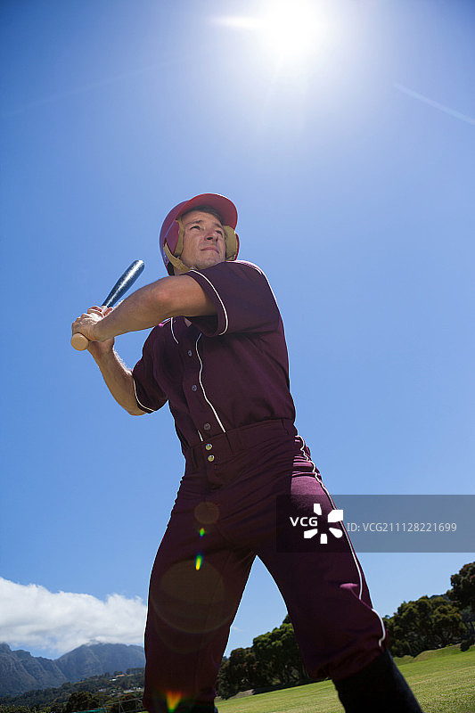 低角度的棒球运动员与球棒对抗天空在晴朗的一天图片素材