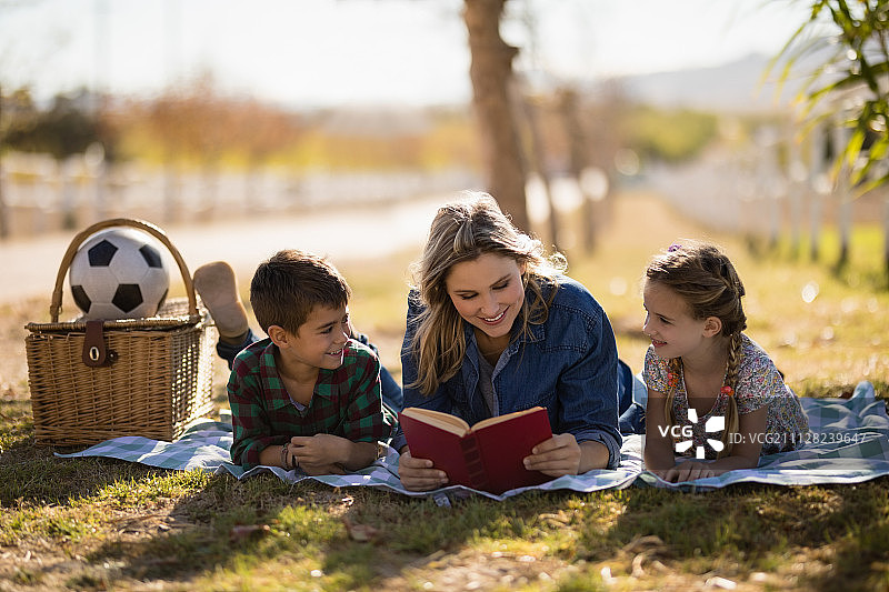 妈妈和孩子们在一个阳光明媚的公园里读小说图片素材