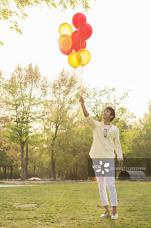 一个年轻人在公园里拿着气球图片素材
