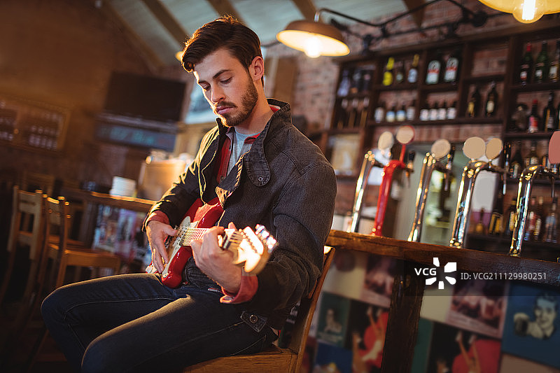 一个年轻人在酒吧里弹吉他图片素材