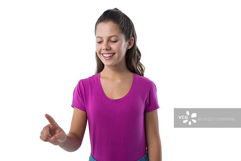 一个十几岁的女孩在白色背景下按住一个看不见的虚拟屏幕图片素材