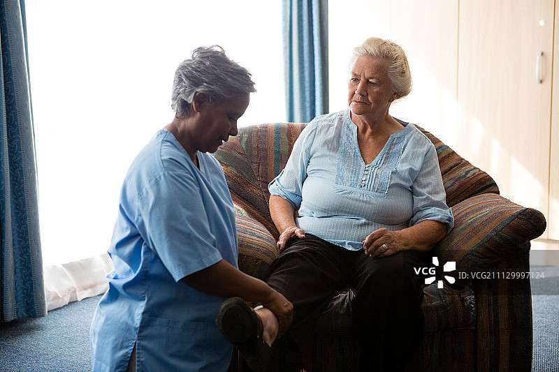 护士在养老院帮助老年妇女伸展双腿图片素材