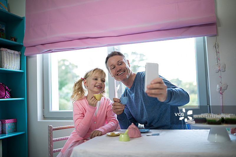 顽皮的女孩和父亲在玩厨房玩具时自拍图片素材
