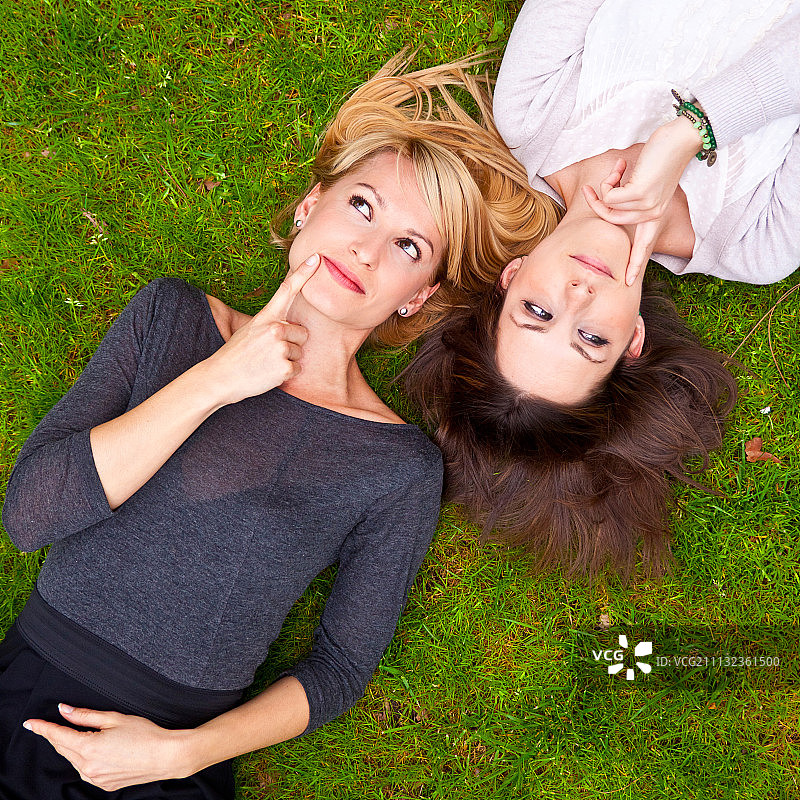 两个女孩在草地上头脑风暴。图片素材