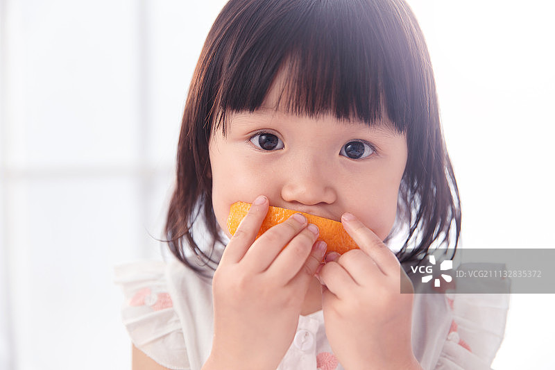 可爱的小女孩在吃橙子图片素材