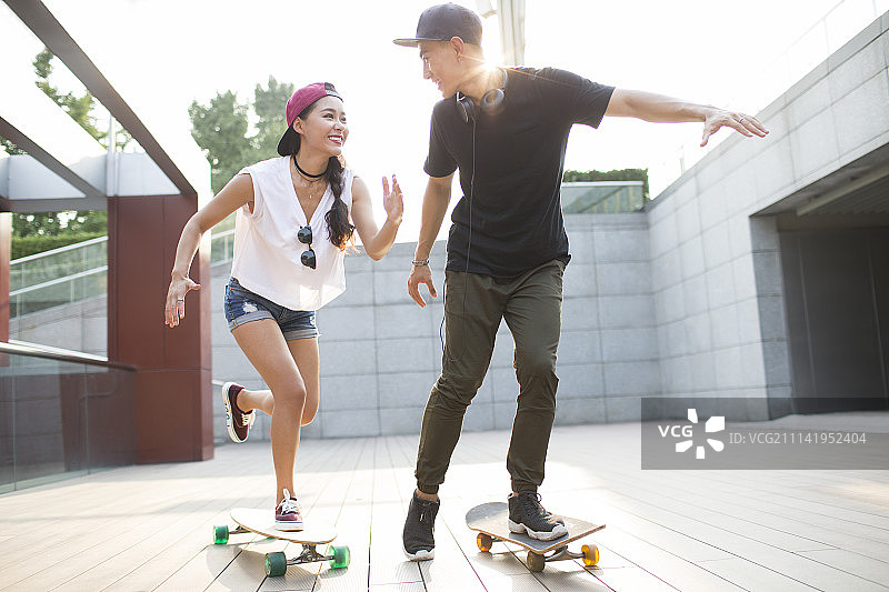 快乐的年轻情侣在滑滑板图片素材