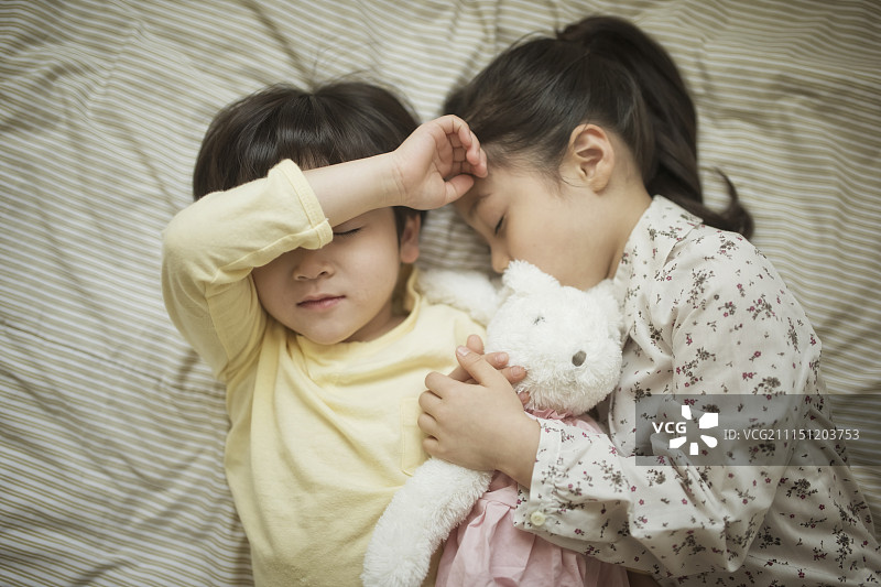 妹妹和弟弟抱着一个兔娃娃躺在床上图片素材