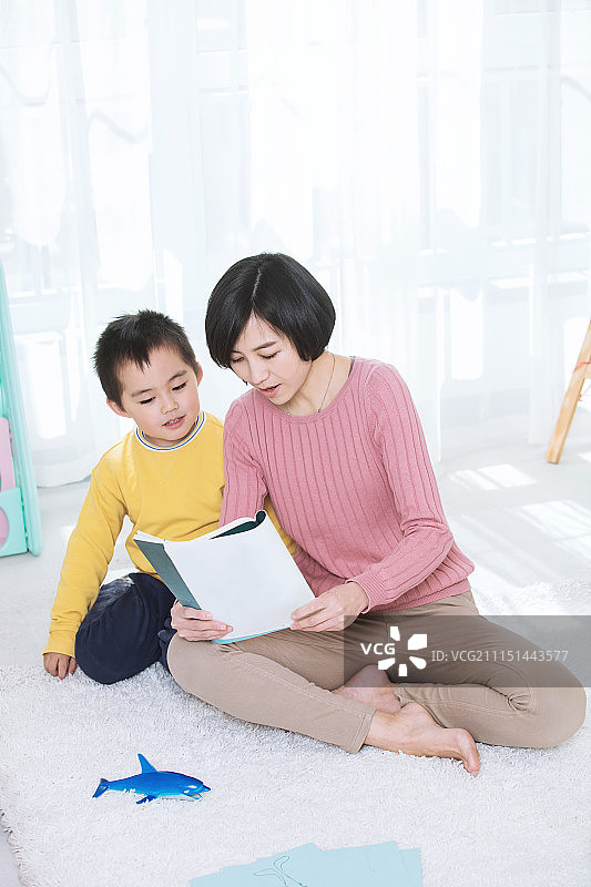 妈妈陪着儿子在客厅里一起看书学习图片素材