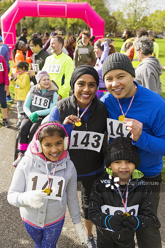在慈善跑步活动中，微笑着佩戴奖牌的家庭合影图片素材