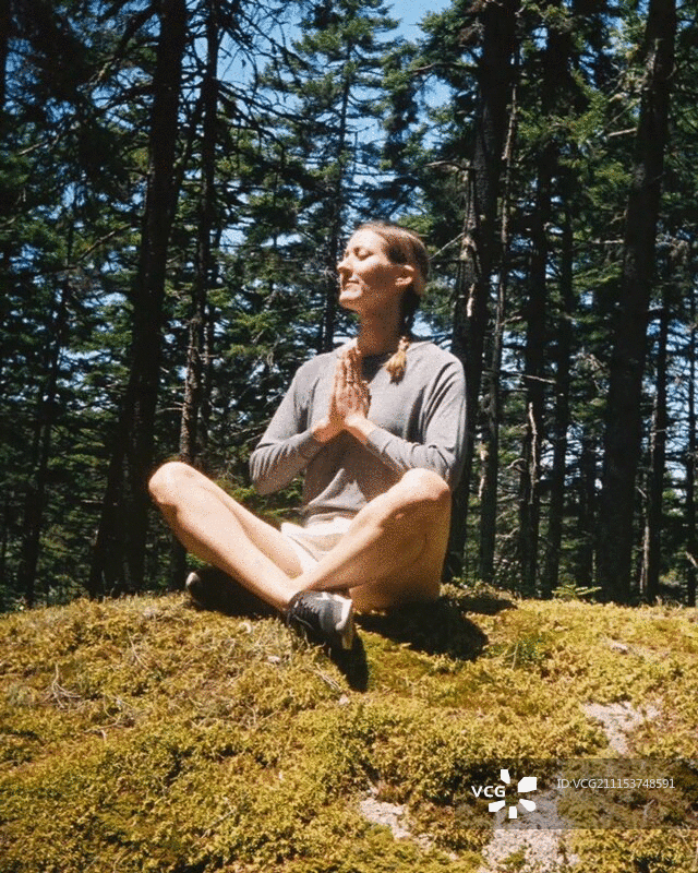 在长满苔藓的地面上做瑜伽的女人图片素材