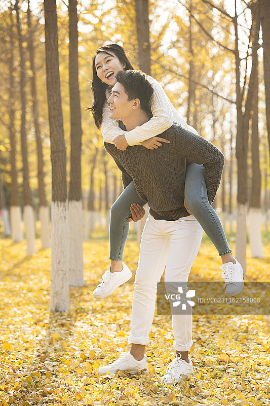 年轻情侣在秋天的树林里玩耍图片素材