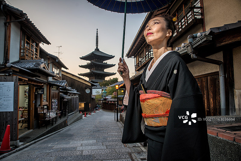 穿着和服和雨伞的日本妇女在古老的日本城镇的街道上图片素材