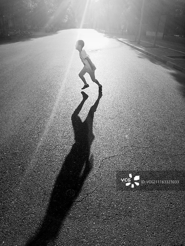 阳光下奔跑踢球的孩子图片素材