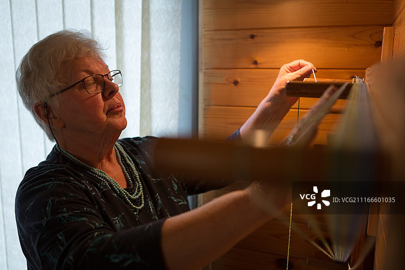年长妇女在织丝绸图片素材