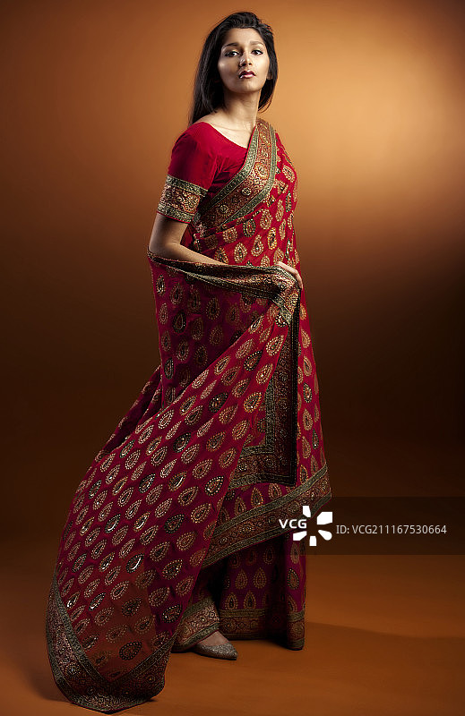 工作室肖像的印度妇女在传统的纱丽服装，以棕色的背景图片素材