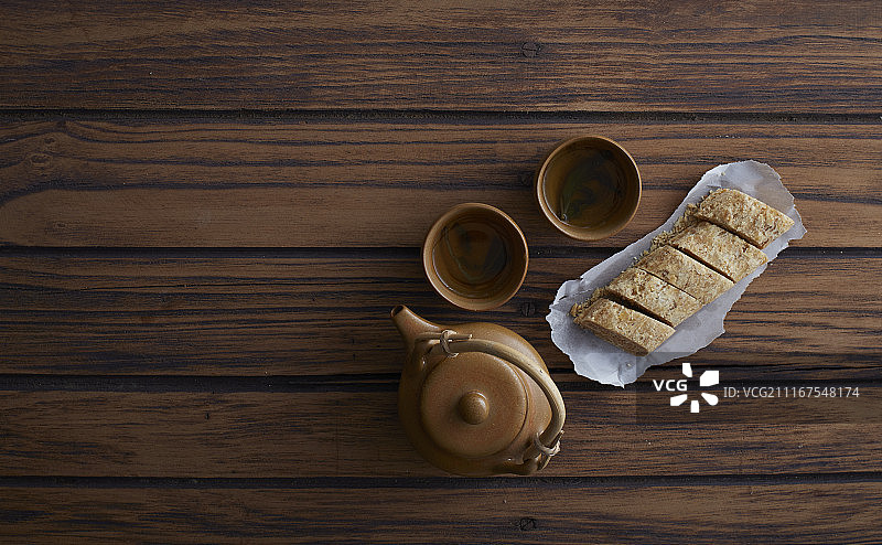 木桌上的糖棒、花生、中国甜点和热茶图片素材