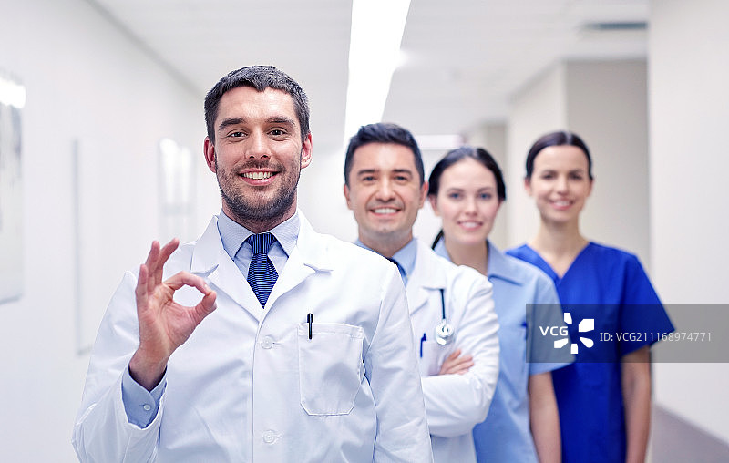 诊所、专业、人群、保健和医学概念——一群开心的医护人员或医生在医院走廊上展示ok手势。一群快乐的医生或医生在医院图片素材