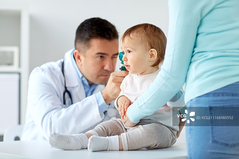 医学、保健、儿科和人的概念——耳鼻喉科医生或医生在诊所用耳镜检查婴儿的耳朵。医生在诊所用耳镜检查婴儿的耳朵图片素材