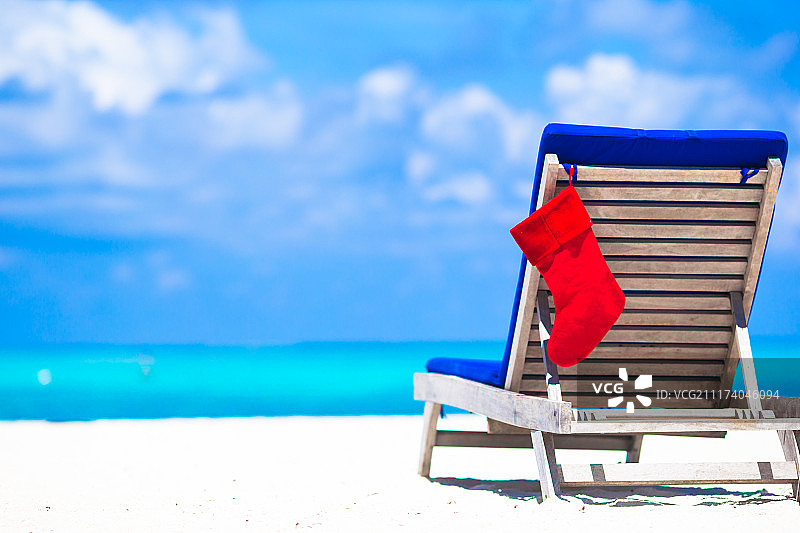 在热带白色海滩的椅子上的红色圣诞袜图片素材