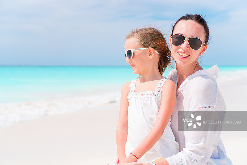 热带海滩上可爱的小女孩和年轻的母亲图片素材