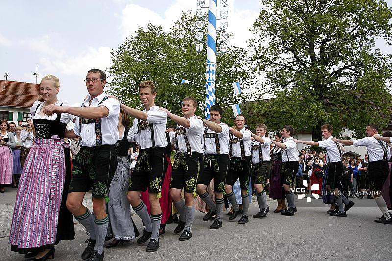 在欧洲巴伐利亚，德国巴伐利亚的Bad Toelz Wolfratshausen区的Eurasburg社区，围绕着五月柱跳舞图片素材