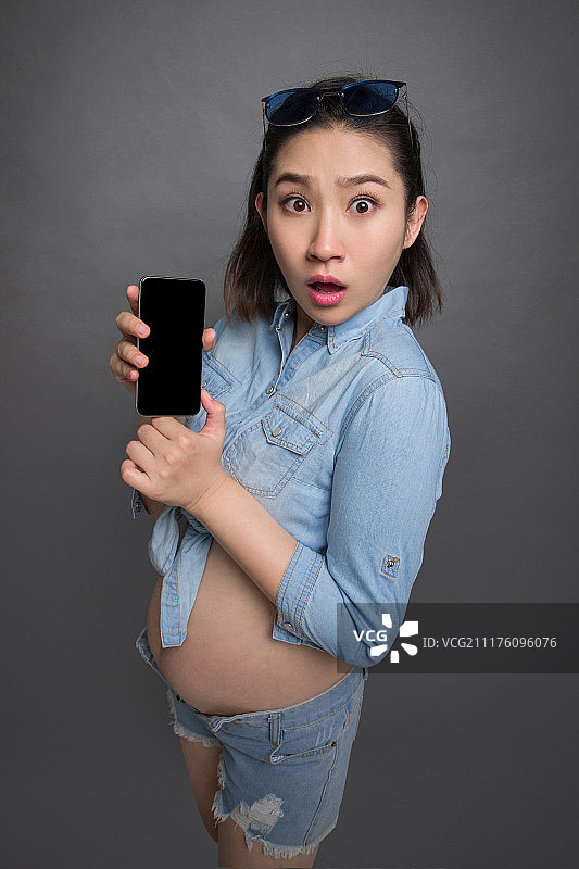 穿着时尚的孕妇拿着手机图片素材