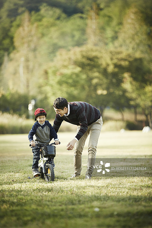 爸爸和小男孩在公园里骑自行车的照片图片素材