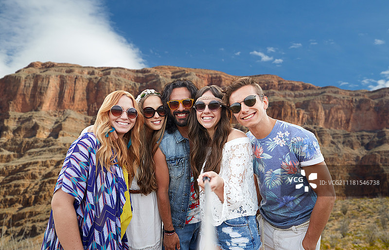 旅游、旅游和科技概念——年轻的嬉皮士朋友们微笑着用智能手机自拍，在大峡谷国家公园的岩石上拍照。朋友们在大峡谷拍自拍。朋友们在大峡谷拍自拍图片素材
