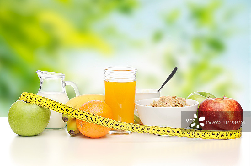 饮食和健康饮食概念-早餐食品和测量卷尺在桌子上的绿色自然背景。桌上放着早餐和卷尺。桌上放着早餐和卷尺图片素材