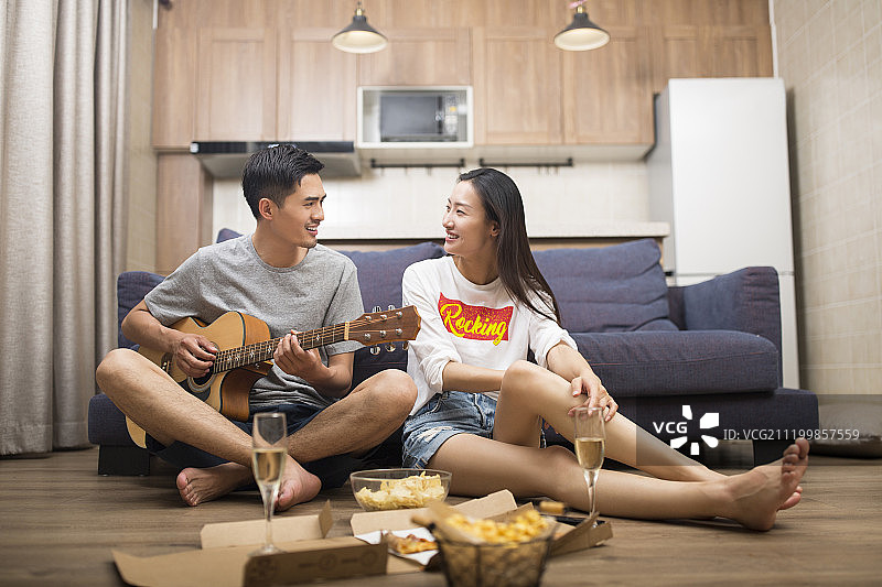 快乐的情侣在客厅演奏吉他图片素材