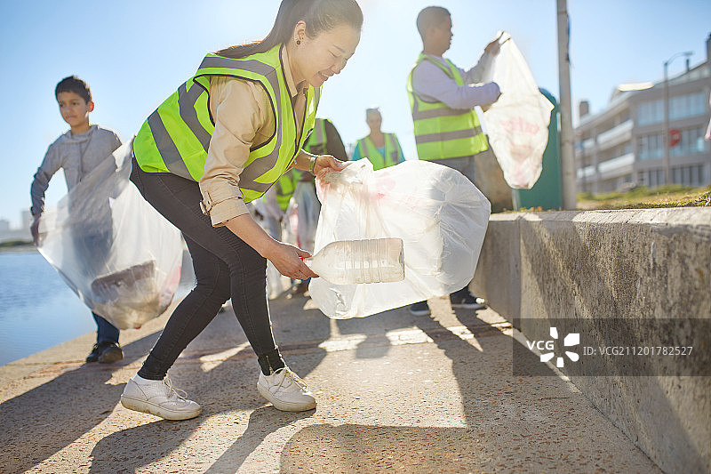 妇女志愿者在阳光明媚的木板路上捡拾塑料垃圾图片素材