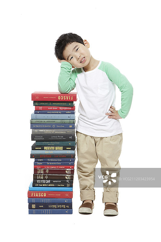 小男孩在一堆书旁边的照片图片素材