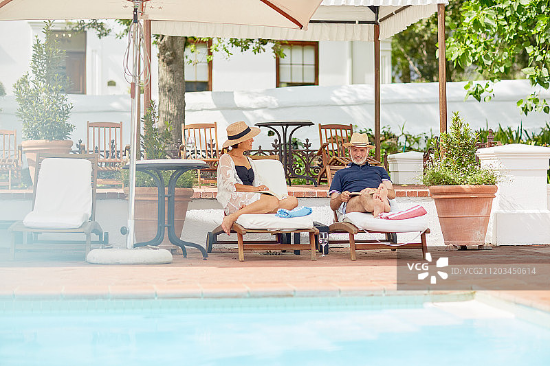 一对成熟的夫妇在度假胜地泳池边的躺椅上放松图片素材