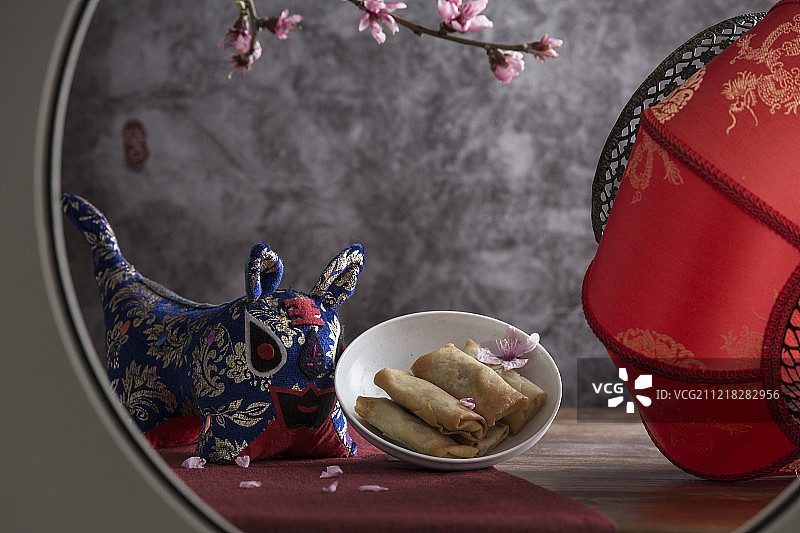 中式圆窗透景创意-春卷、布老虎和红灯笼静物图片素材