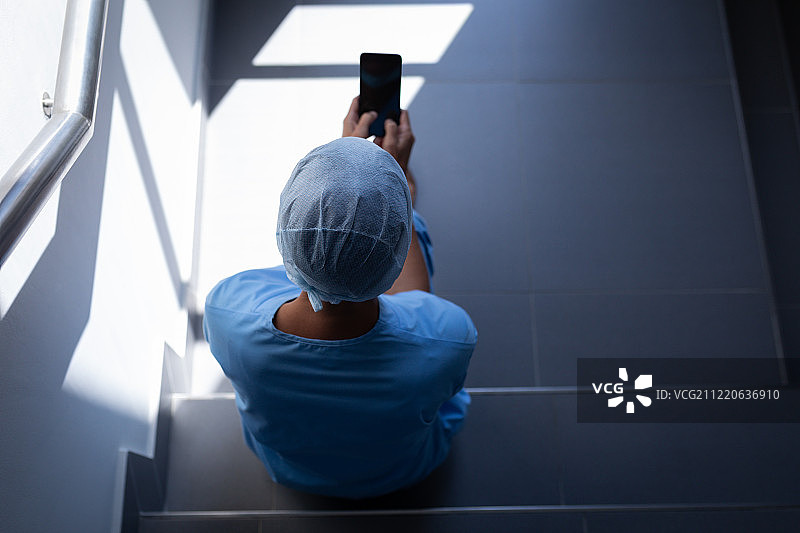 一名白人女外科医生坐在医院楼梯上使用手机的俯视图图片素材