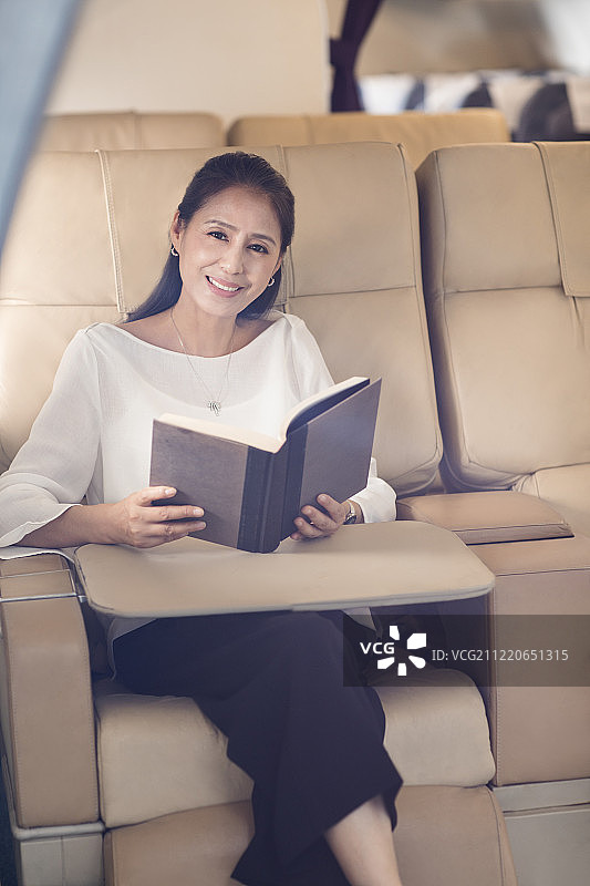 优雅的中年女士在机舱内读书图片素材