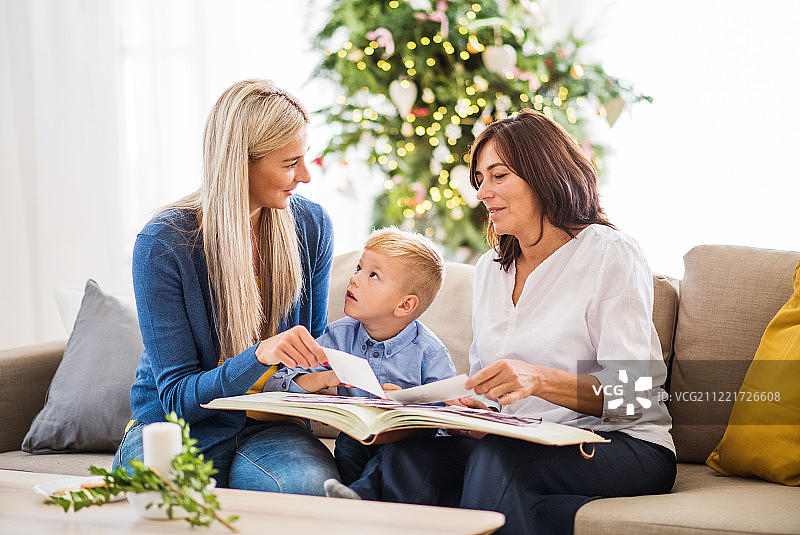 圣诞节的时候，一个小男孩和妈妈、奶奶在家里看照片。图片素材