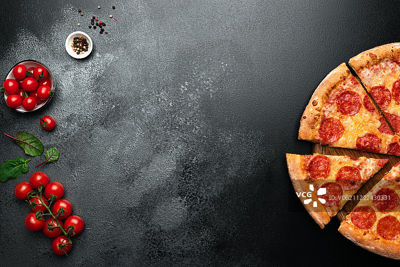 黑石板背景上的辣香肠披萨图片素材