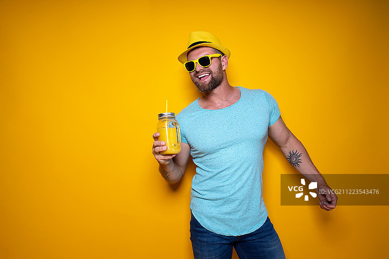 男子与明亮的橙色饮料摆姿势图片素材