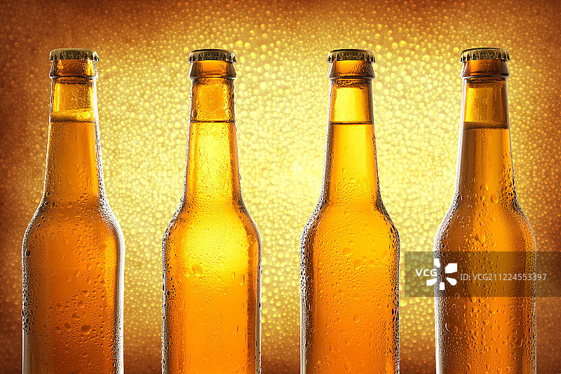 四排封闭的玻璃瓶和新鲜的啤酒在金色的背图片素材