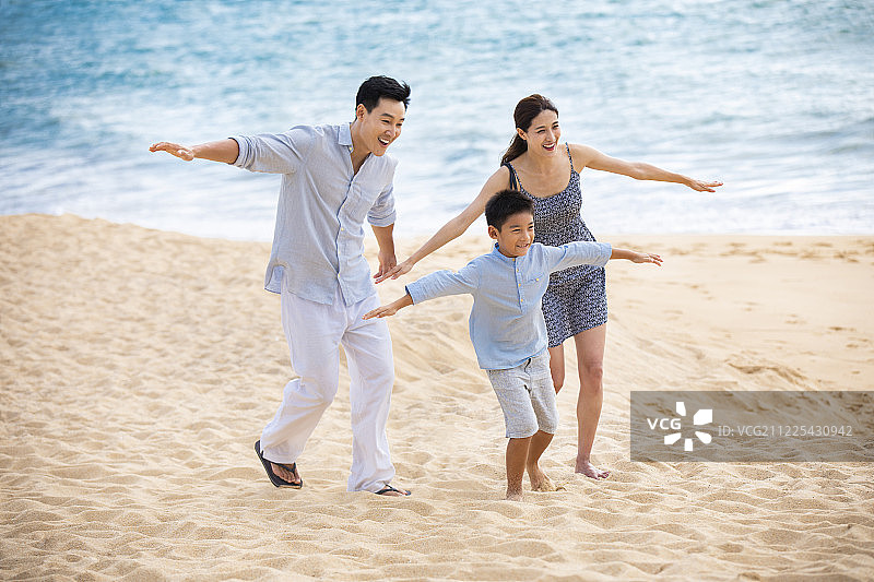 快乐的年轻家庭在沙滩玩耍图片素材