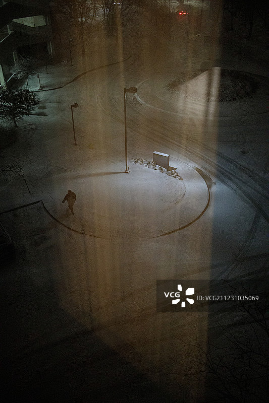 透过酒店的窗户，可以看到一个在暴风雪中孤独行走的人图片素材