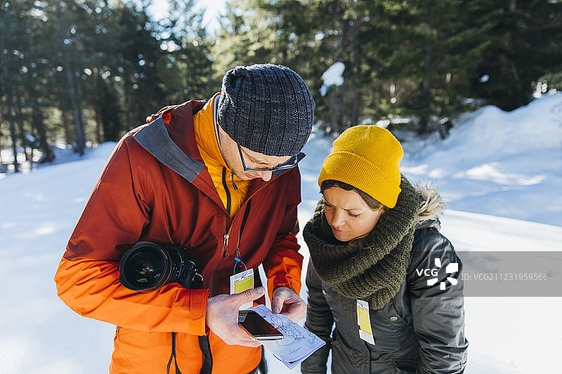 在加拿大不列颠哥伦比亚省的惠斯勒，一名男子和一名女子在冬季徒步旅行时查看地图图片素材