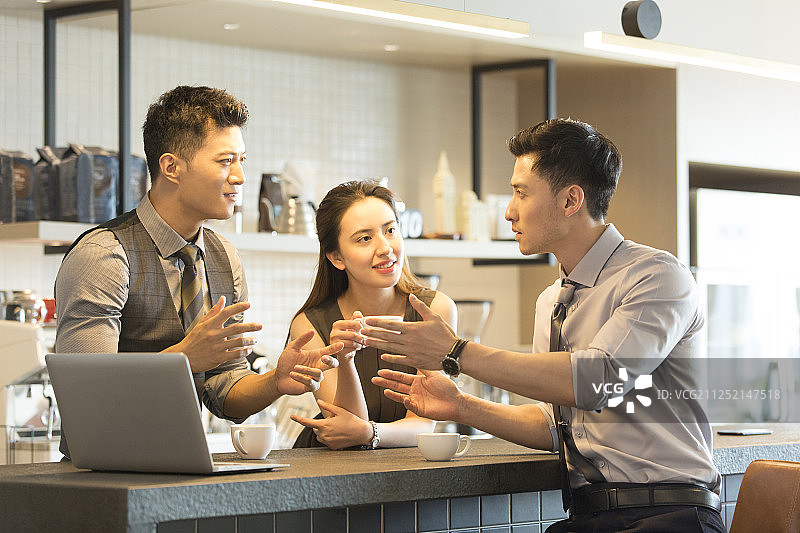 三个青年商务男女喝咖啡使用笔记本电脑聊工作在咖啡馆图片素材