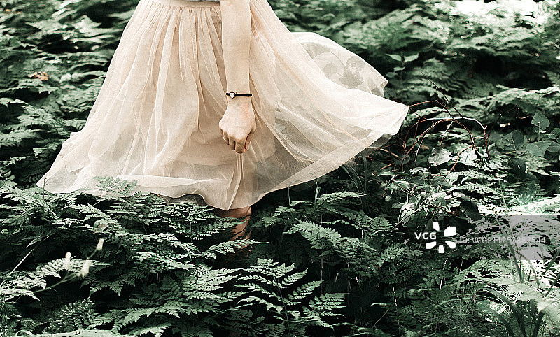夏日森林里，独自一人穿着裙子的女孩。图片素材