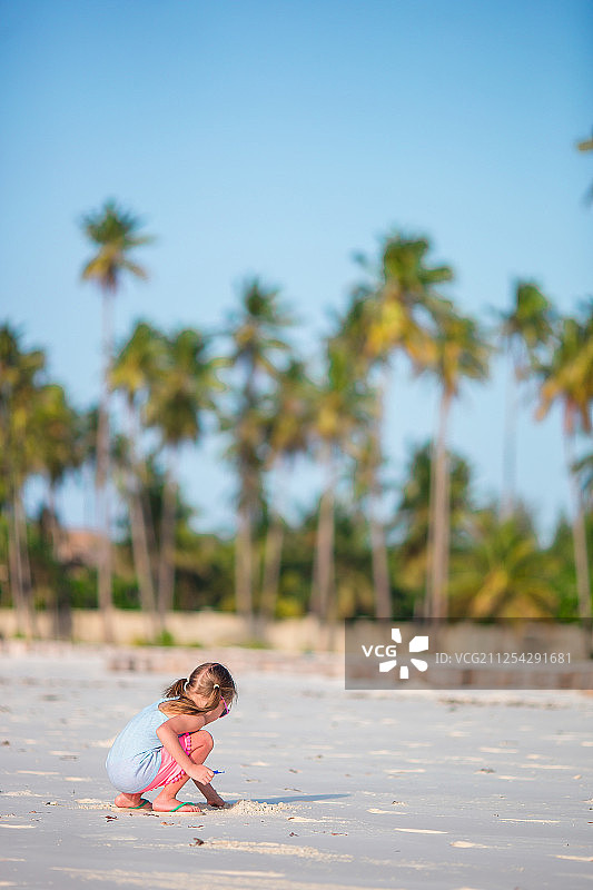 可爱的小女孩在白色的沙滩上画画图片素材