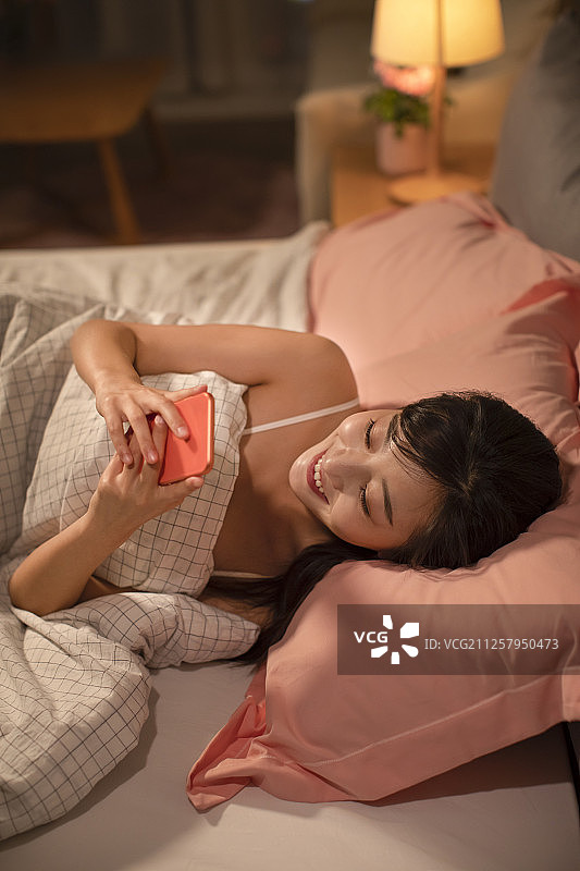 年轻女士睡前玩手机图片素材