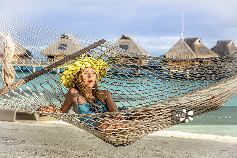 一个年轻的女孩躺在一个豪华海滩度假村的海滩上的吊床上图片素材
