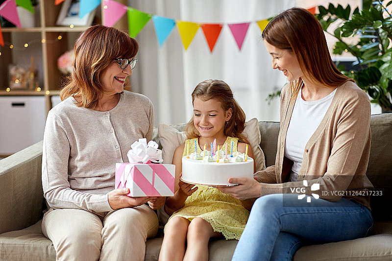 家庭、世代和庆祝概念-微笑的母亲、女儿和祖母与礼物盒和生日蛋糕，并在家里十支蜡烛。母亲，女儿和祖母过生日图片素材