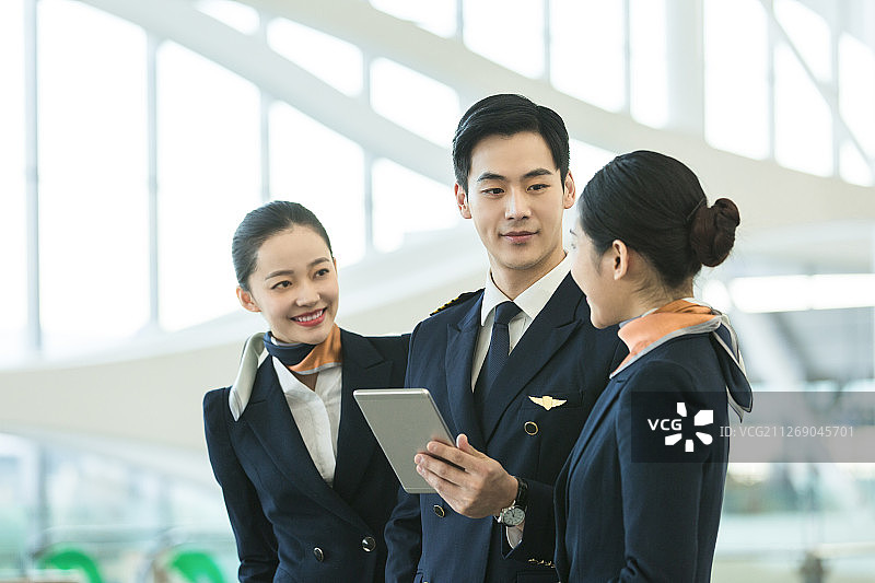 飞机机长和两名空姐在机场使用平板电脑沟通工作图片素材